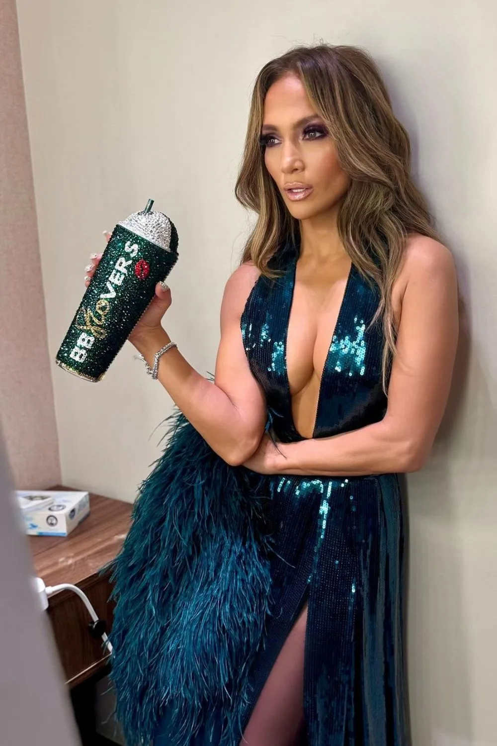 famous singer in sequin dress holding a bottle covered in crystals