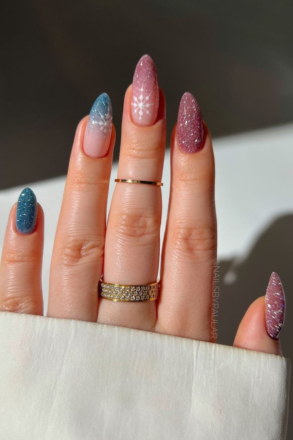 Sparkly pink and blue nails with white snowflake accents