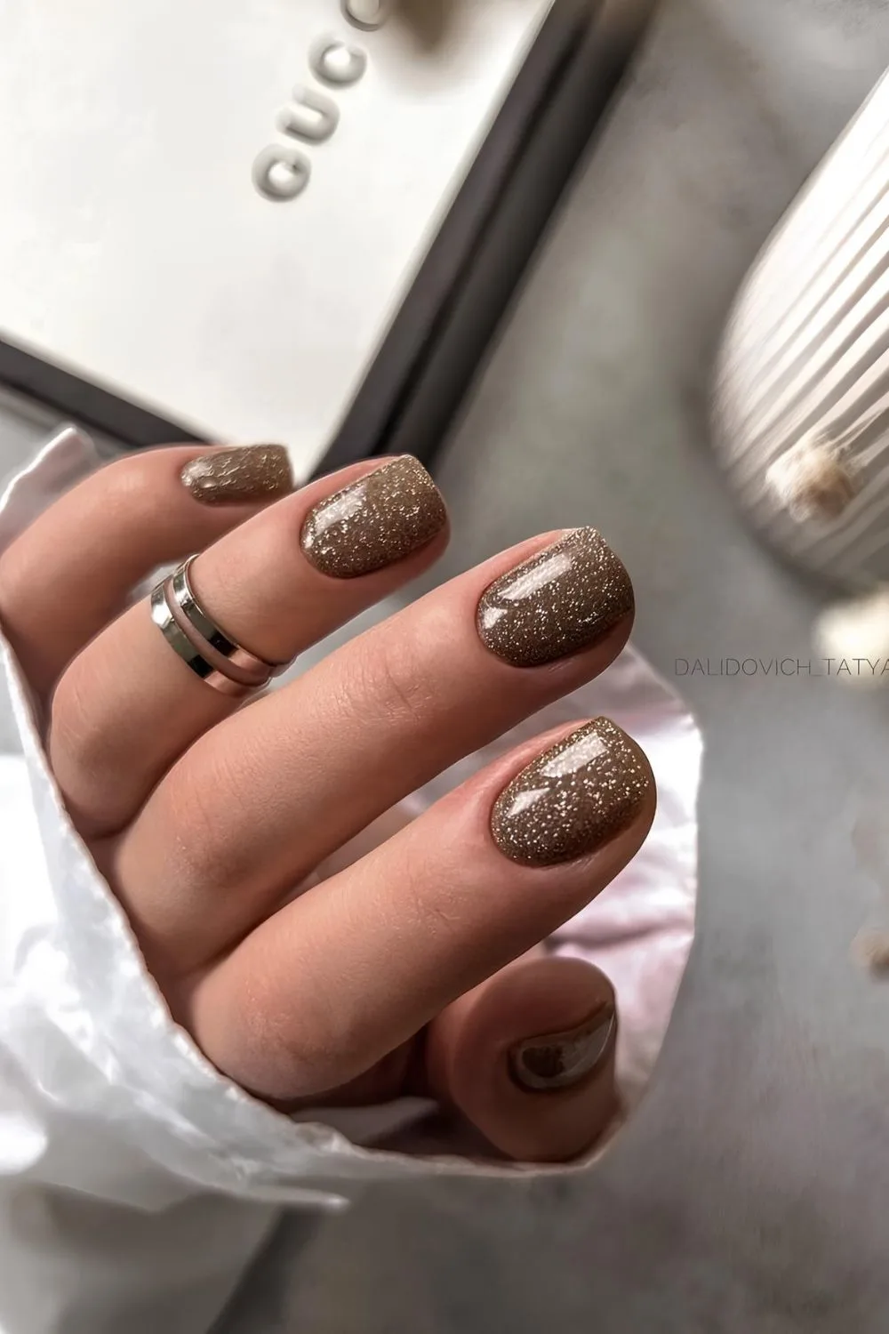 Chunky gold glitter nails on a brown base