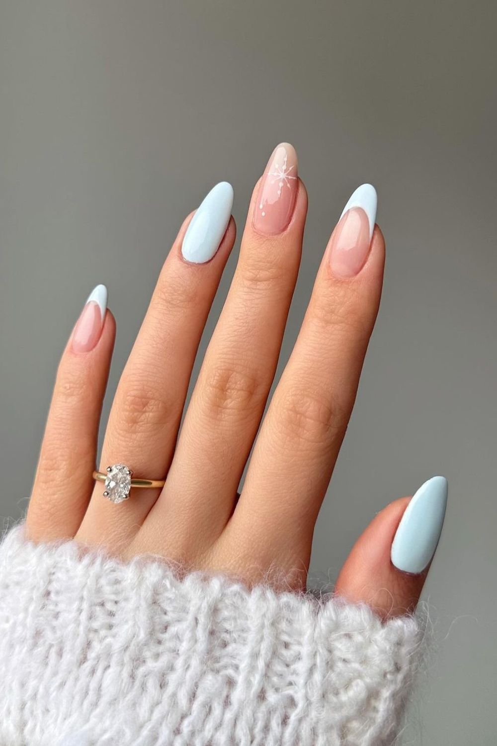 Combination of baby blue solid and French nails with a nude accent with a white snowflake design 