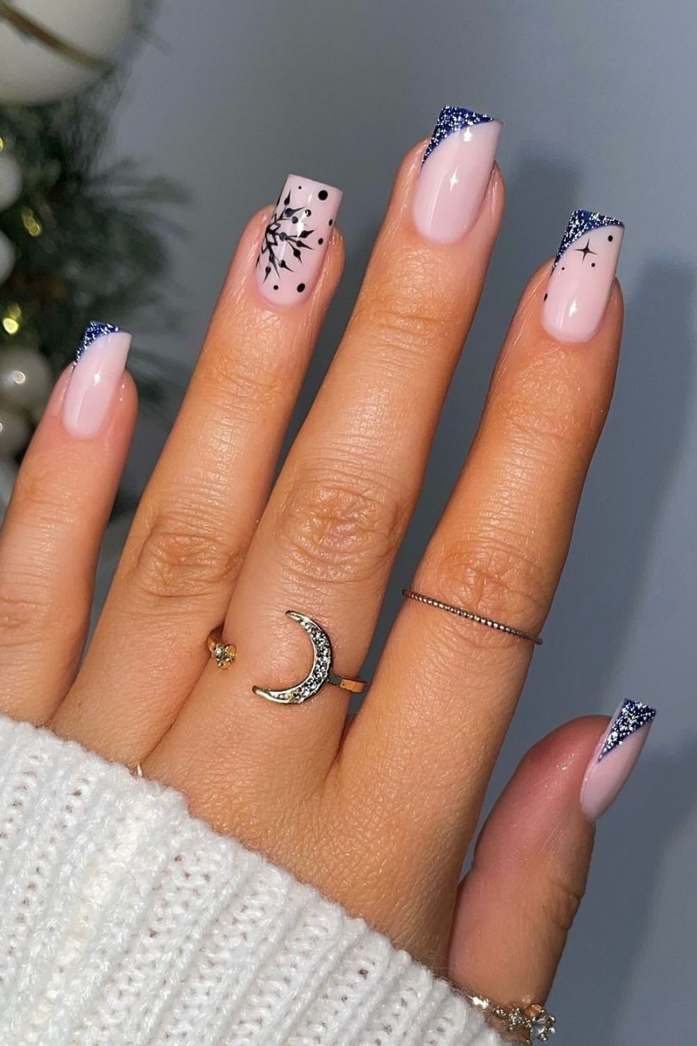 Glittery dark blue side French tip nails with a black snowflake and tiny celestial motif accents