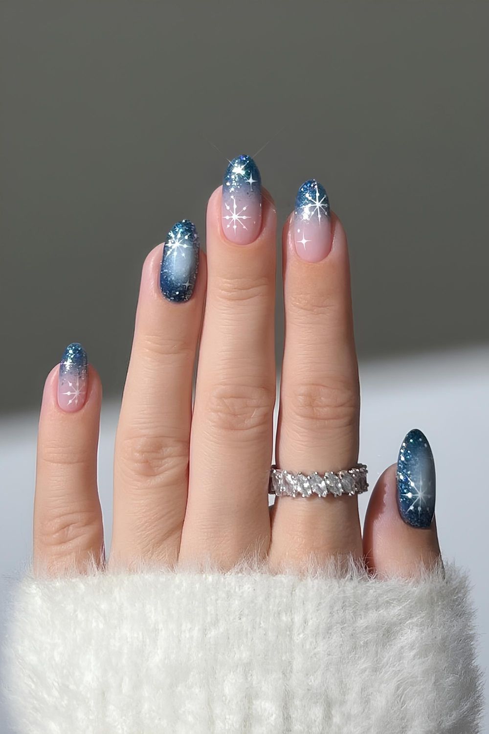 Dark glittery blue ombre nails with sheer bases with dazzling white star accent nails