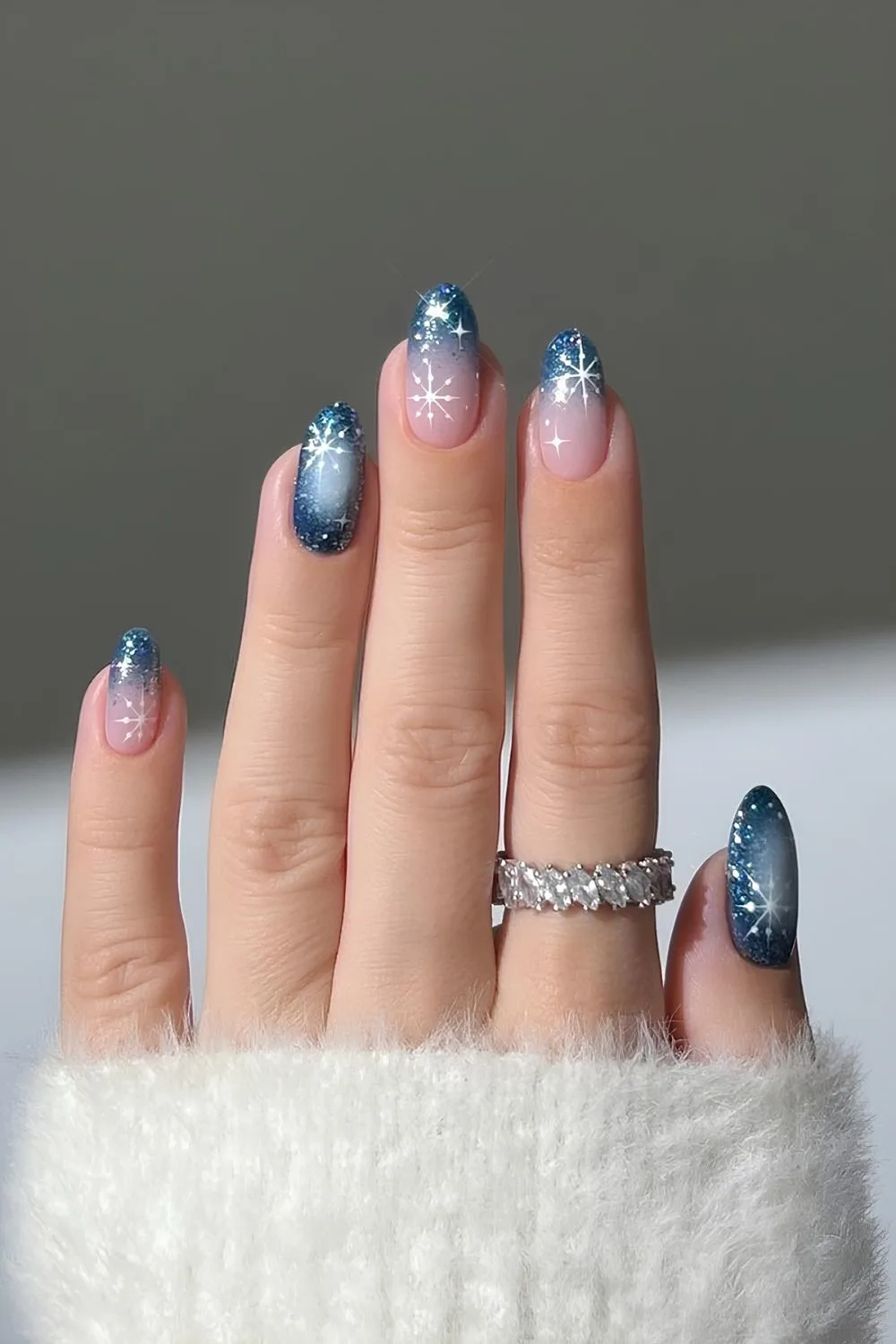 Dark glittery blue ombre nails with sheer bases with dazzling white star accent nails