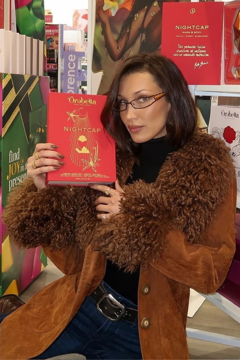 Famous model Bella Hadid wearing chocolate nails while holding a book