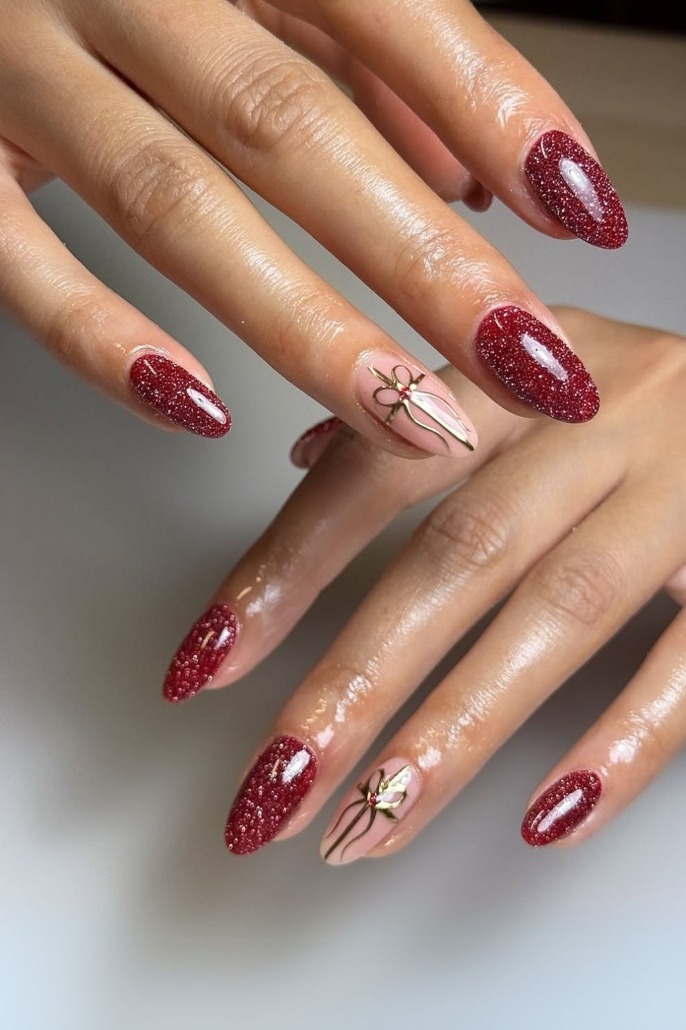 Glittery dark red nails with gift bow art