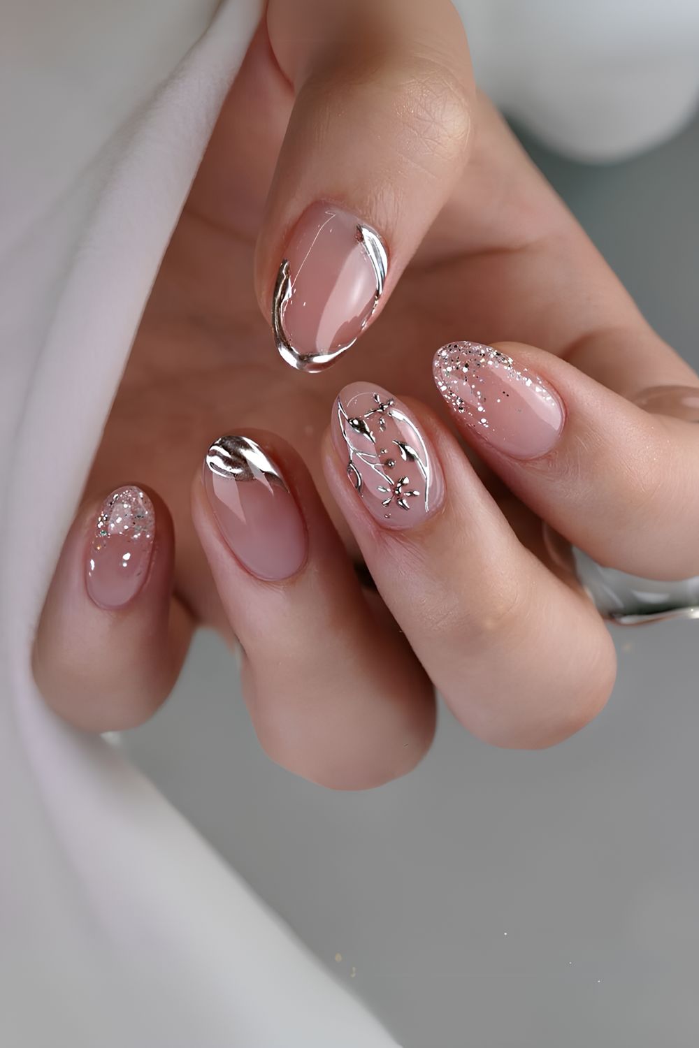 Nude nails with silver chrome and glitter accents