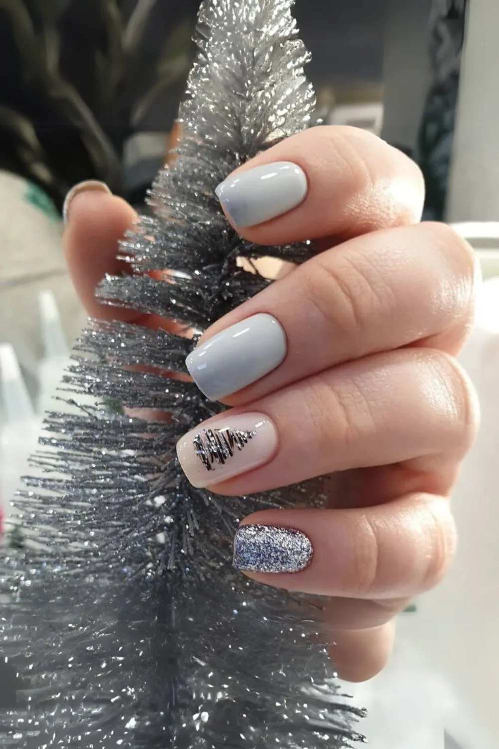 Pale blue nails with blue glitter accent nail, and black and glitter blue Christmas tree accent