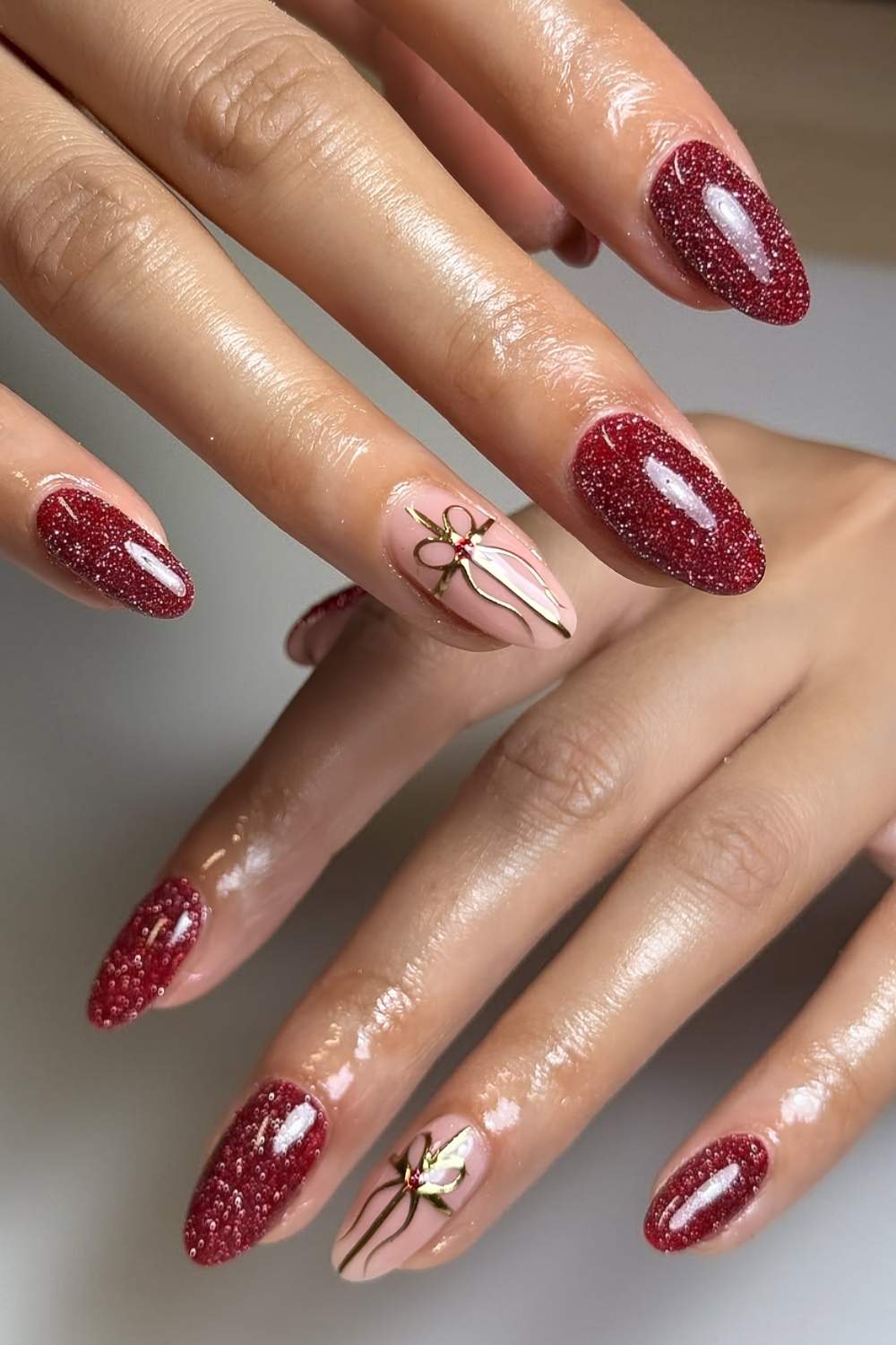 Red glitter nails with gold chrome bows