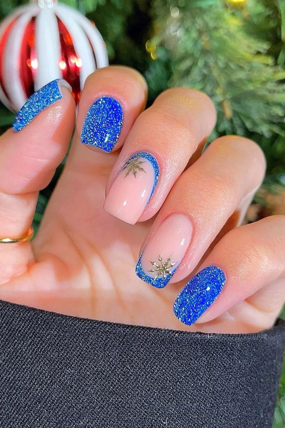 Reflective blue glitter nails mixed with nude accents featuring gold snowflakes and glittery blue French tips