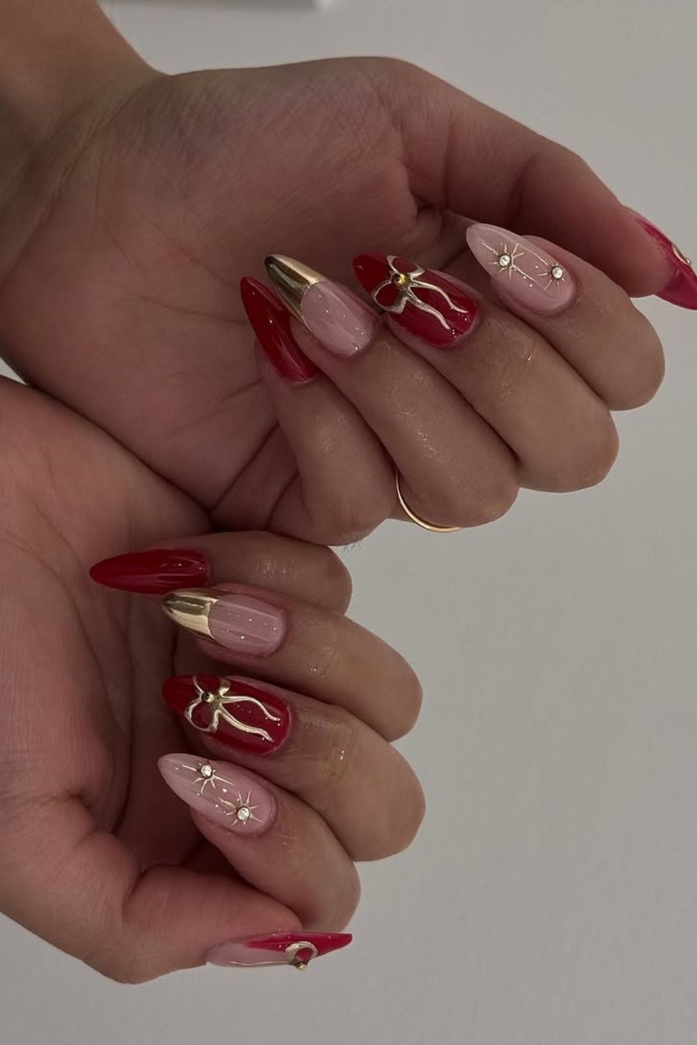 Solid red nails with chrome French tips and bow details and gold celestial rhinestone details on accent nails