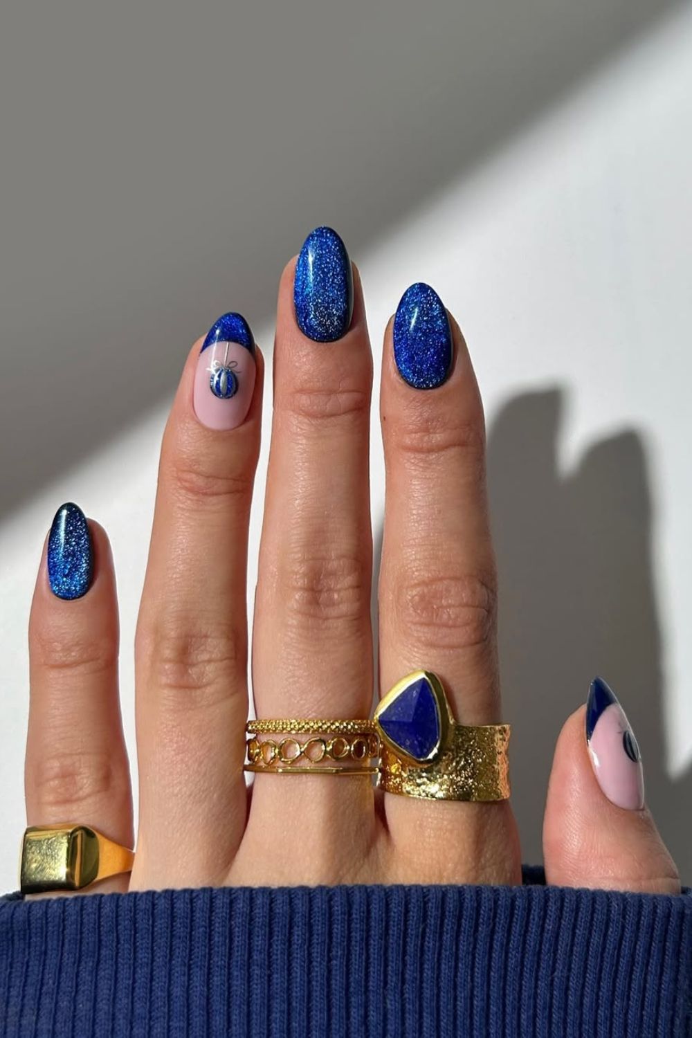 Sparkly cobalt blue nails with a nude accent nail with festive blue bauble