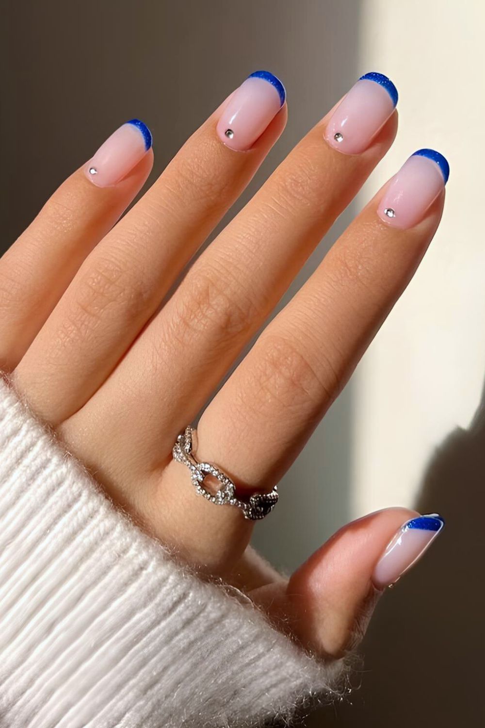 Blue French tip nails with rhinestone accents