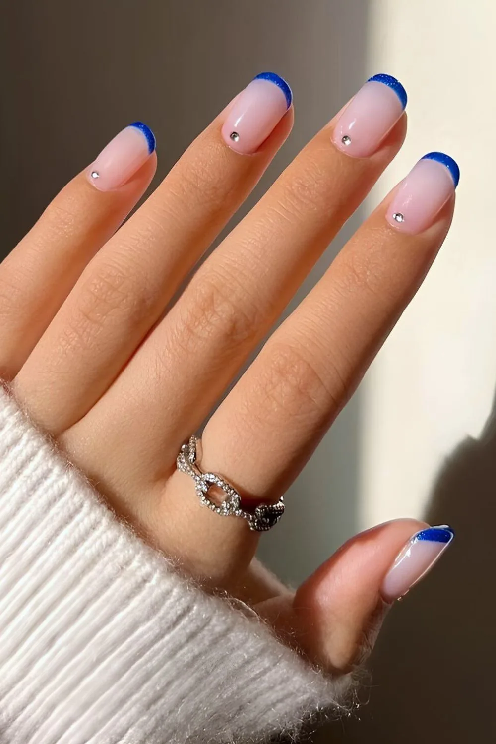 Blue French tip nails with rhinestone accents