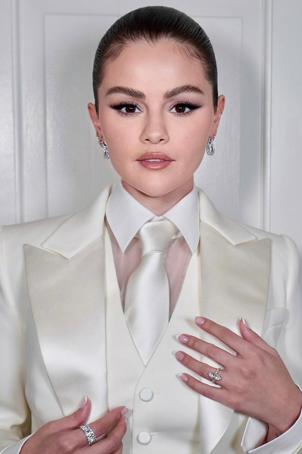 Famous singer posing in white suit with white on white French nails