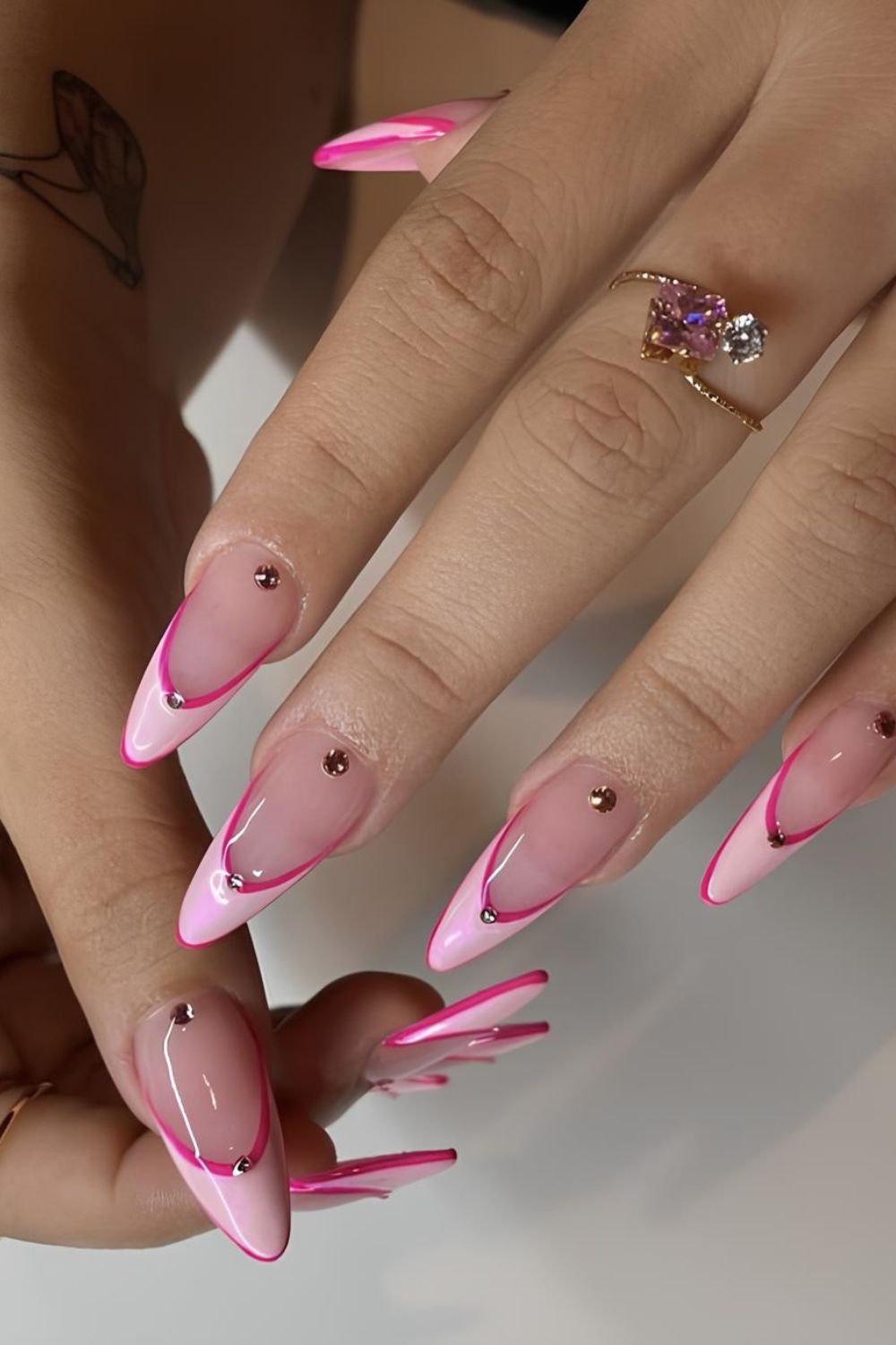 Light pink French tip nails with hot pink outline and rhinestone accents