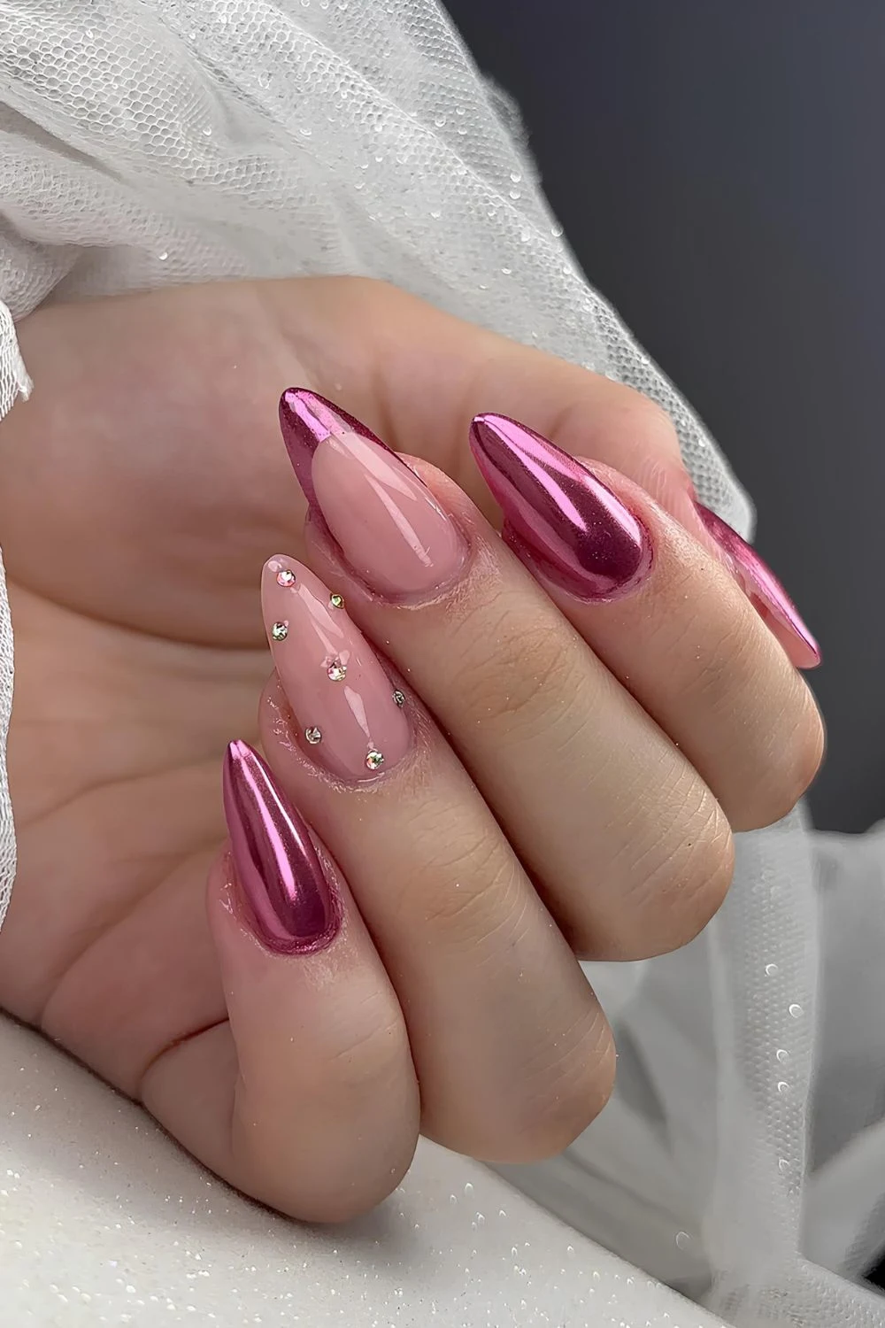 Metallic pink nails with rhinestone accents