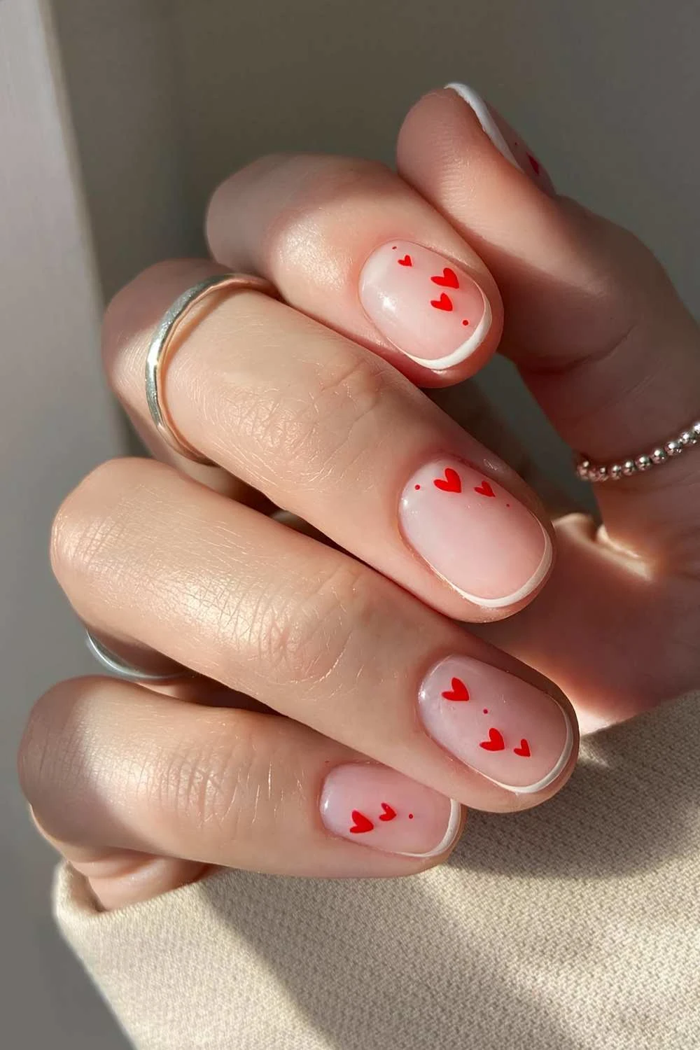 Micro white French nails with red hearts