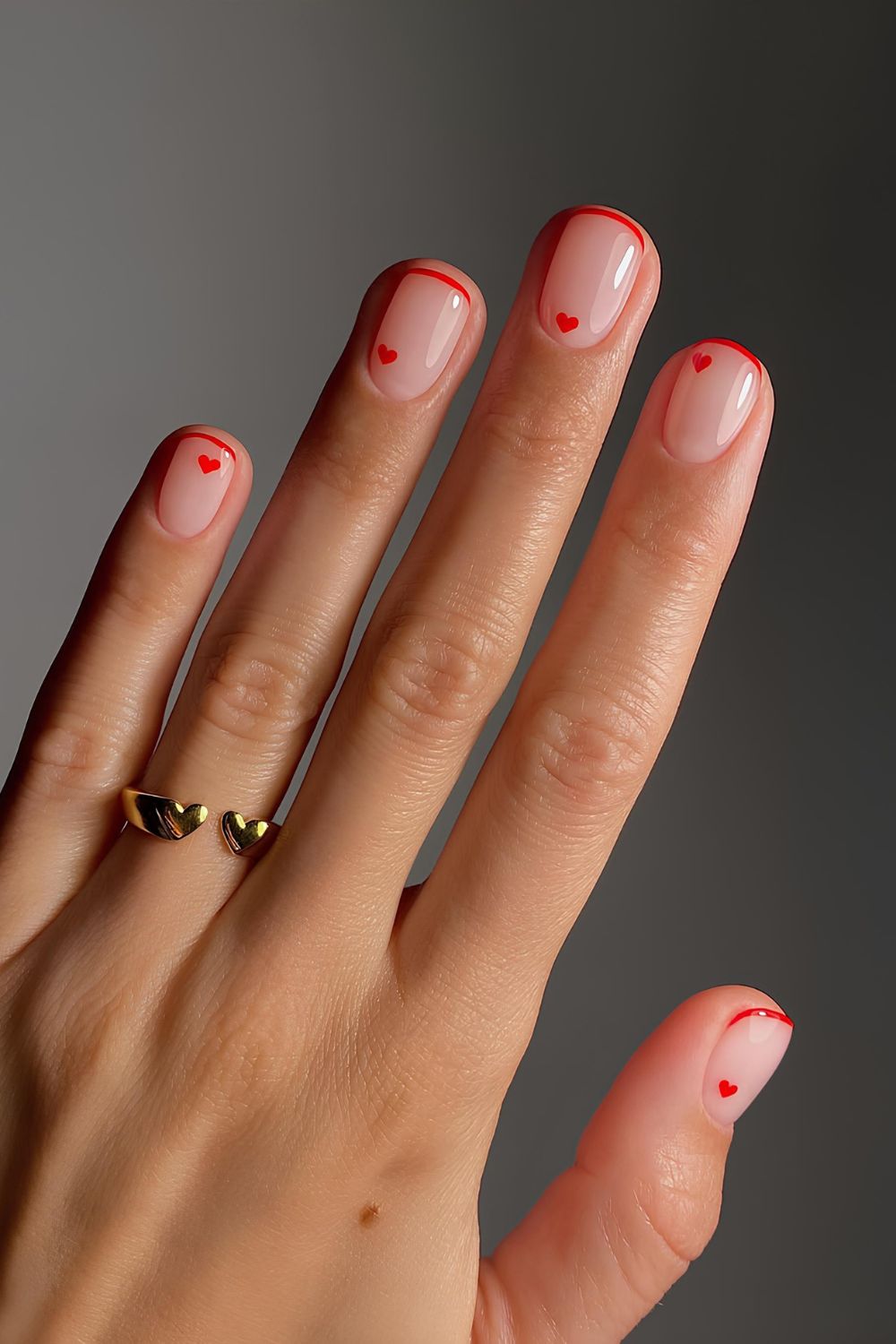 Minimalistic neutral nails with thin red tips and heart accents