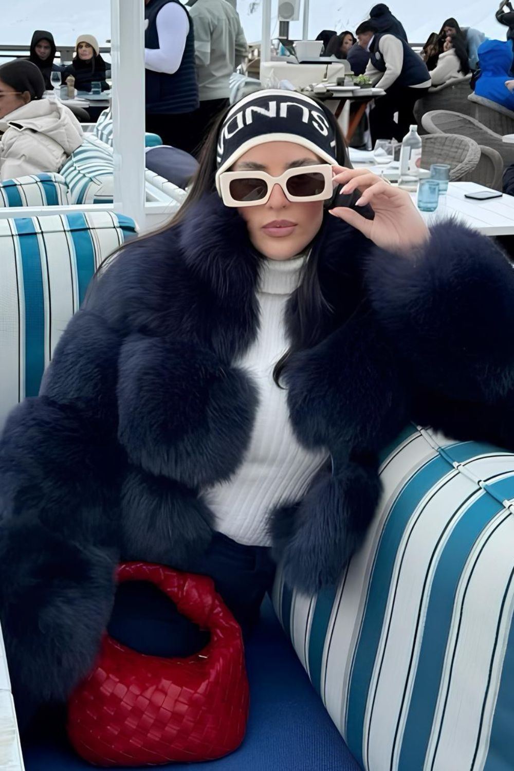 Navy blue fur coat with red bag and white sunglasses paired with headband