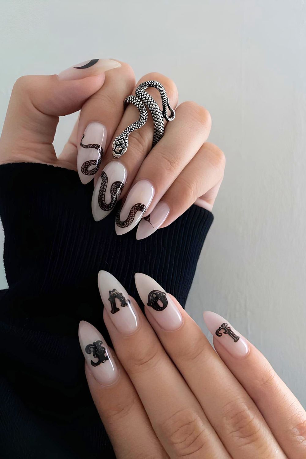 Nude nails with black snake designs on one hand and LOVE snake print lettering on the other hand