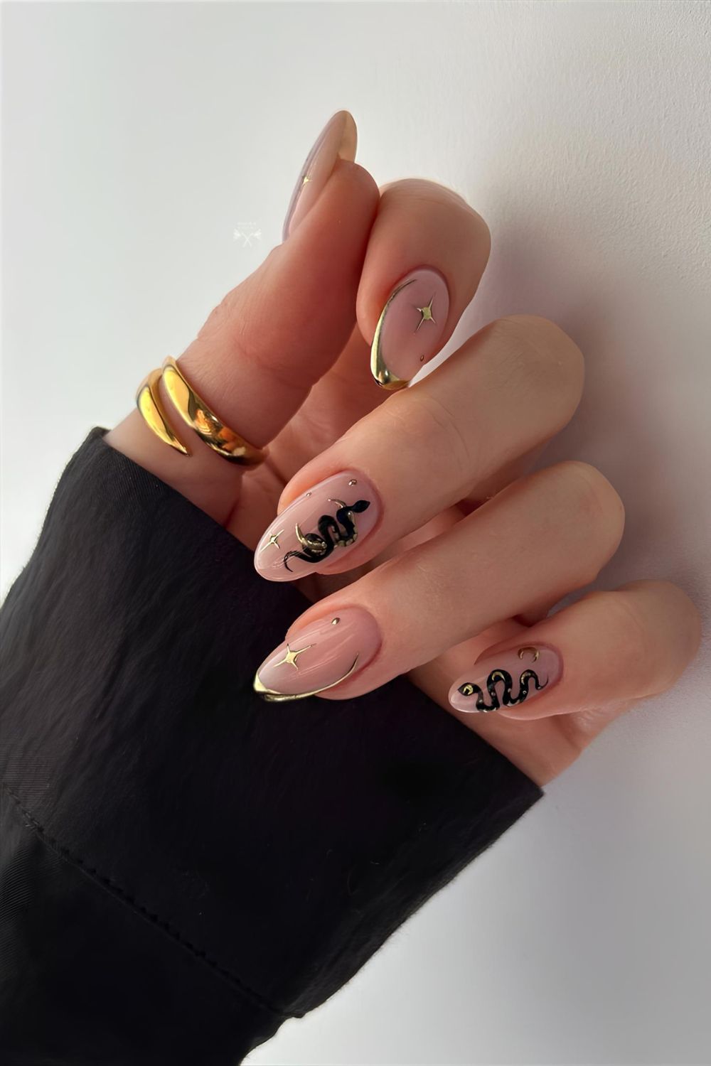 Nude nails with golden chrome frenchies and starburst details and black snake accent nails