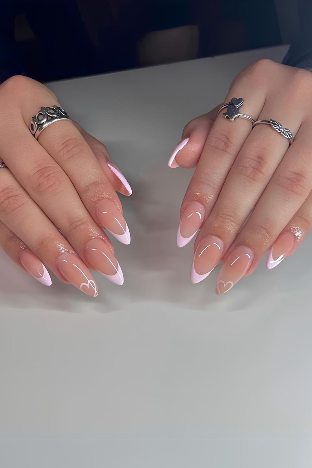 Pink French tips with heart outline on accent nails