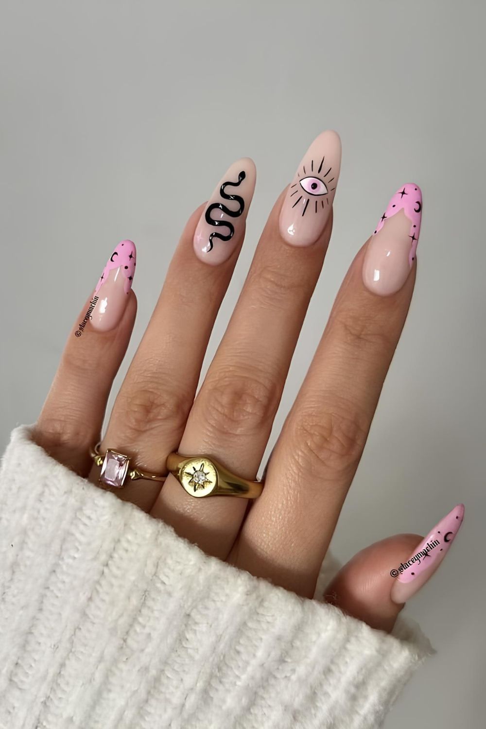 Pink nails with black snake design, all-seeing eye and celestial motives