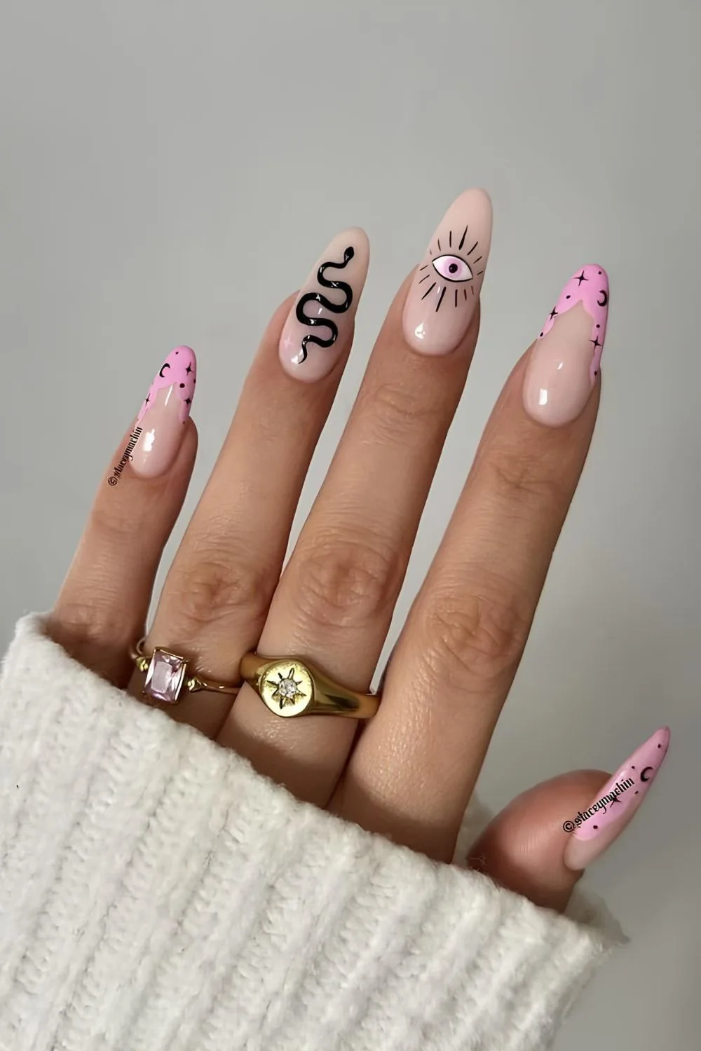 Pink nails with black snake design, all-seeing eye and celestial motives