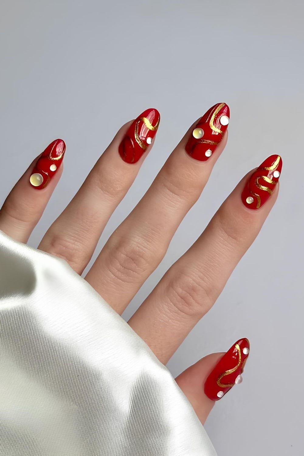 Red nails with rhinestones and gold abstract snake pattern