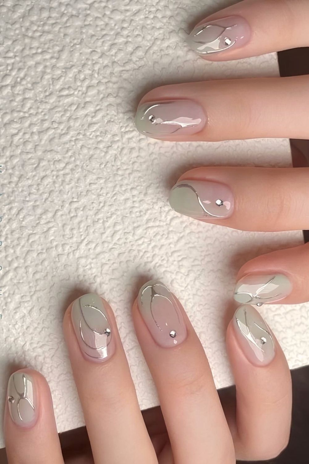 Sage green ombre nails with silver chrome accents and rhinestones