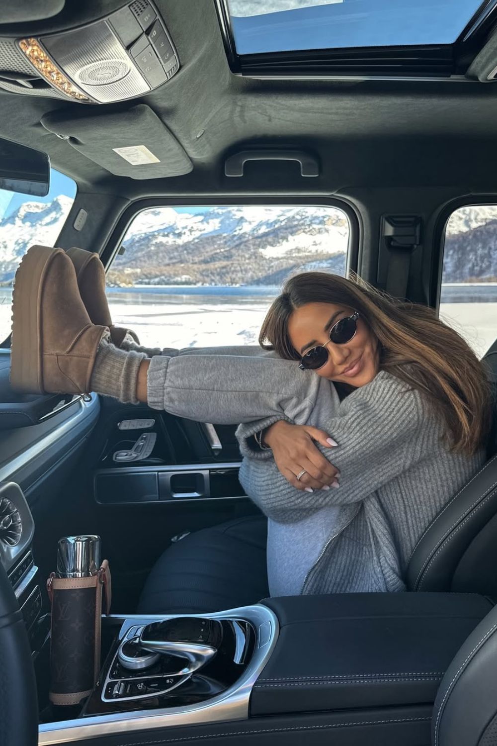 Smiling woman posing in gry sweatpants with boots in car