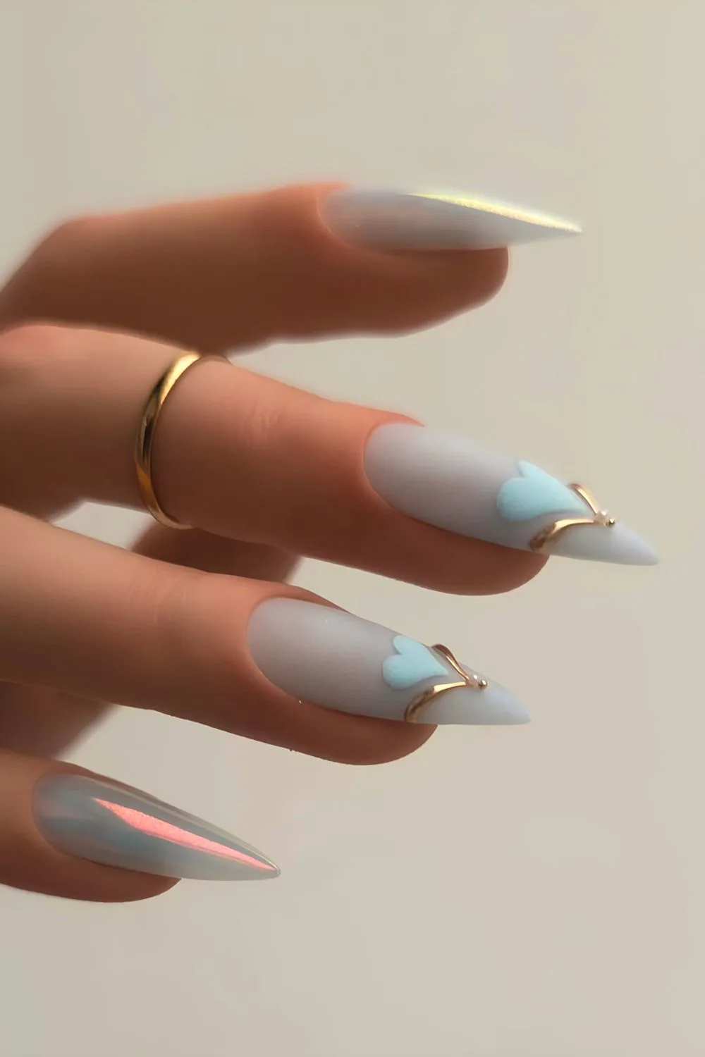 Soft blue nails with heart accents and gold jewelry