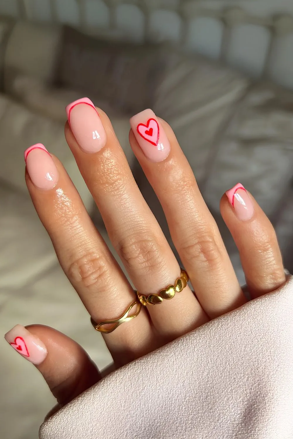 Soft pink based nails with red and pink tips with heart accent