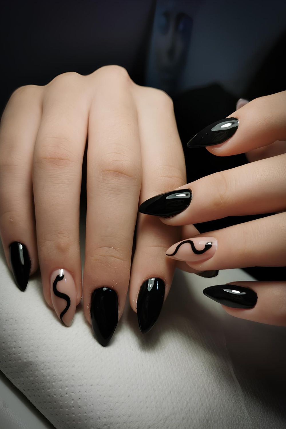 Solid black nails and nude accent nails with black snake design