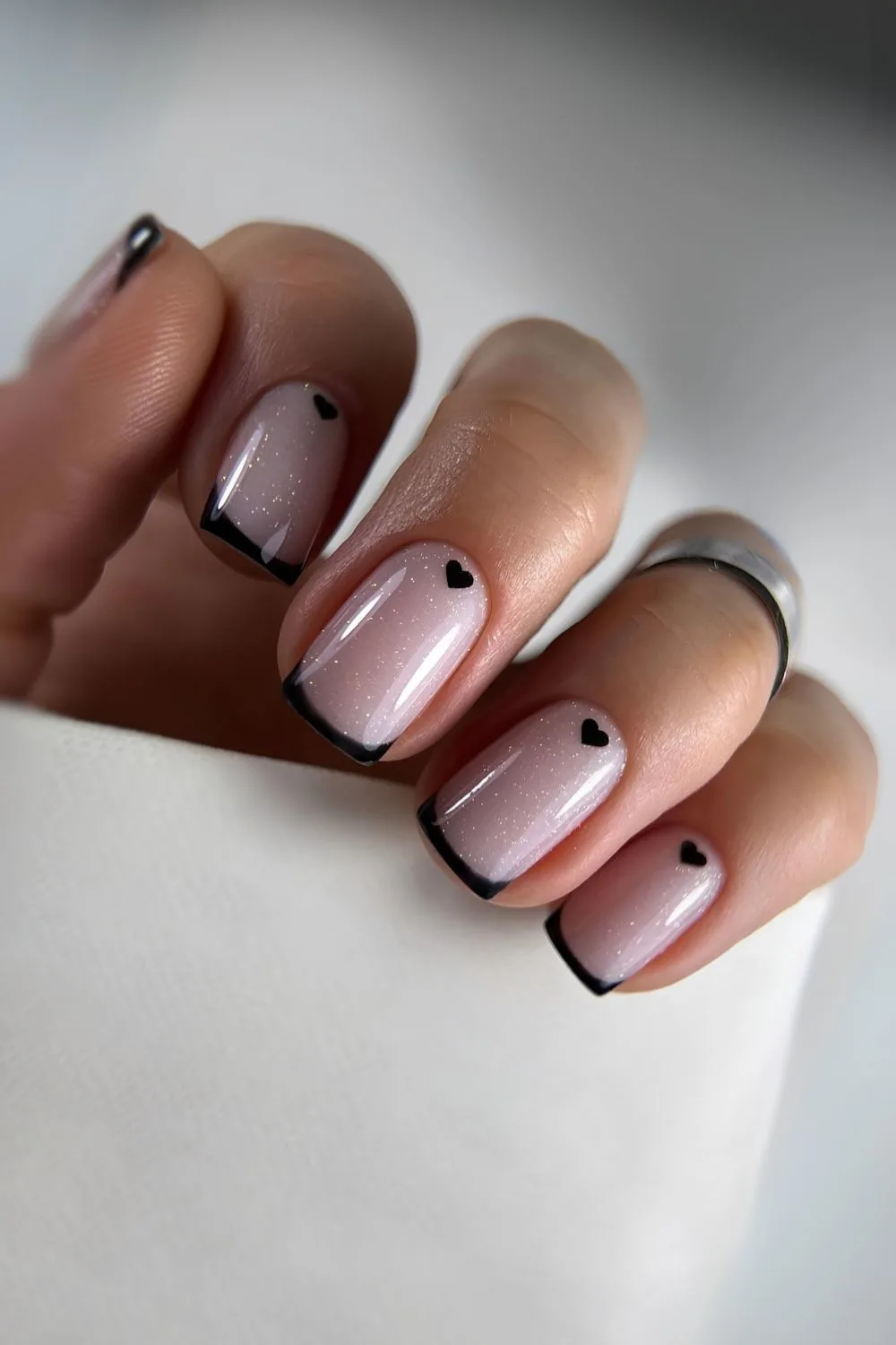 Black French tips on a white base with heart accents