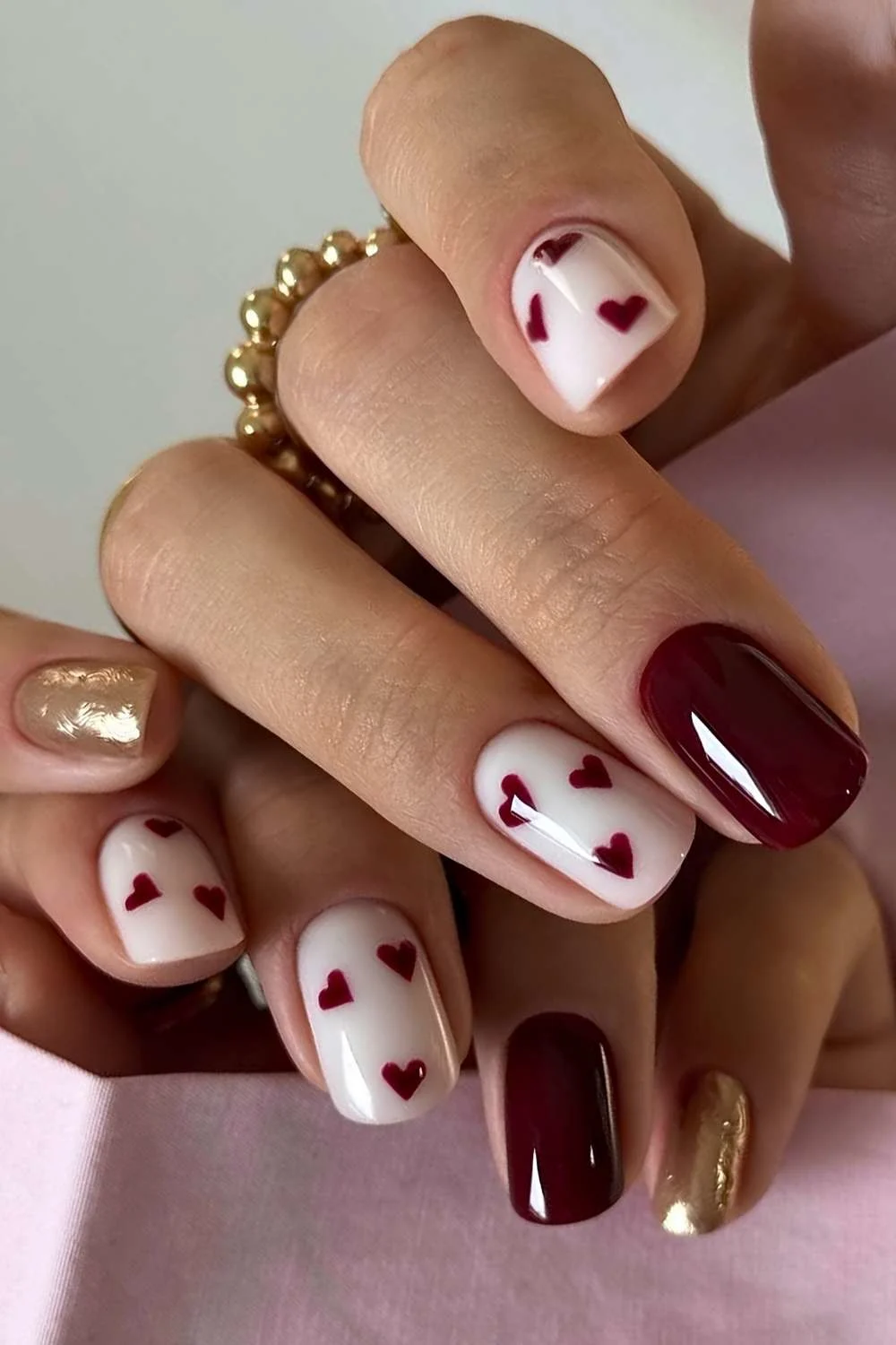 Burgundy and white nails with gold and heart accents