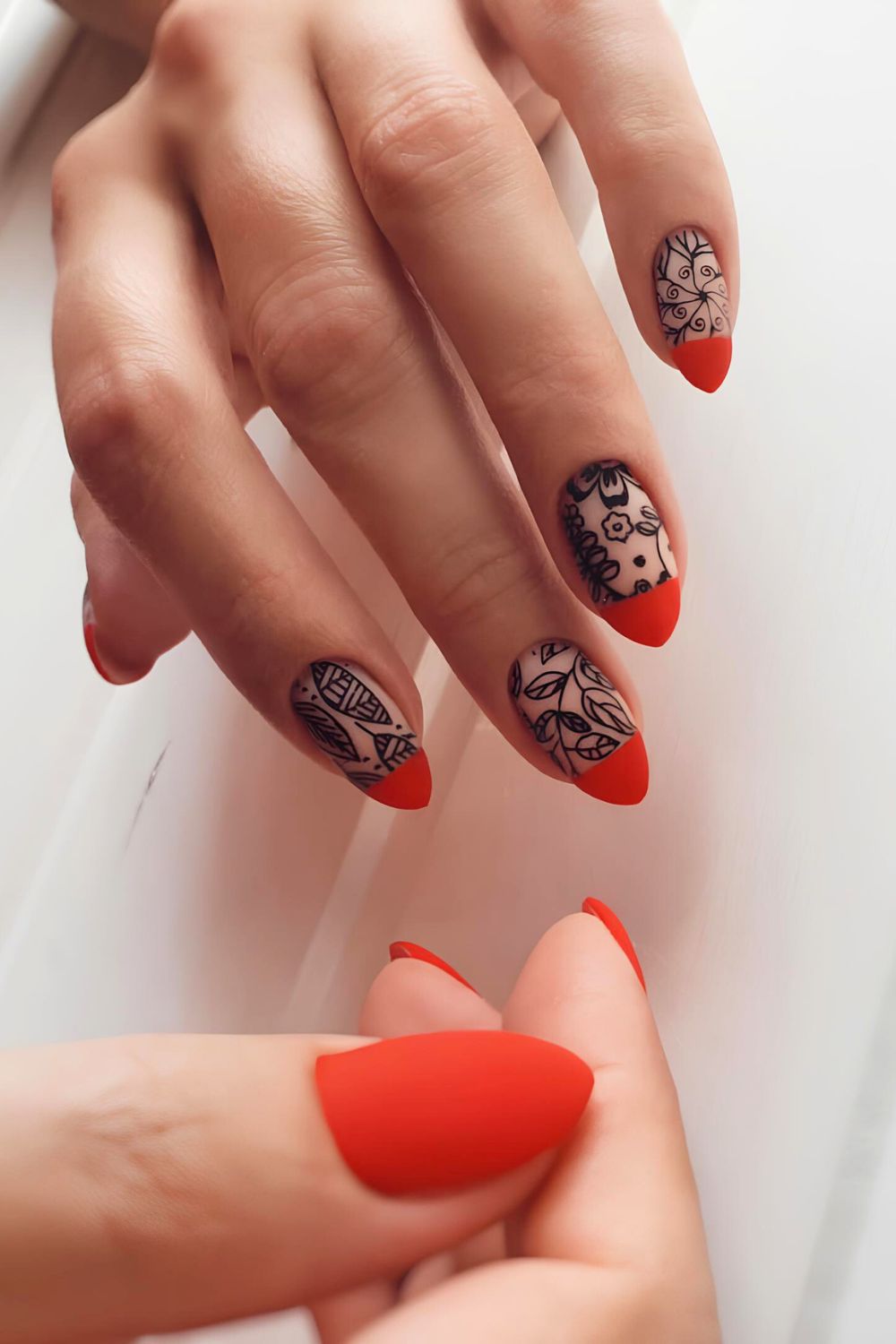 Red French tip nails with black leaves and flowers in matte design