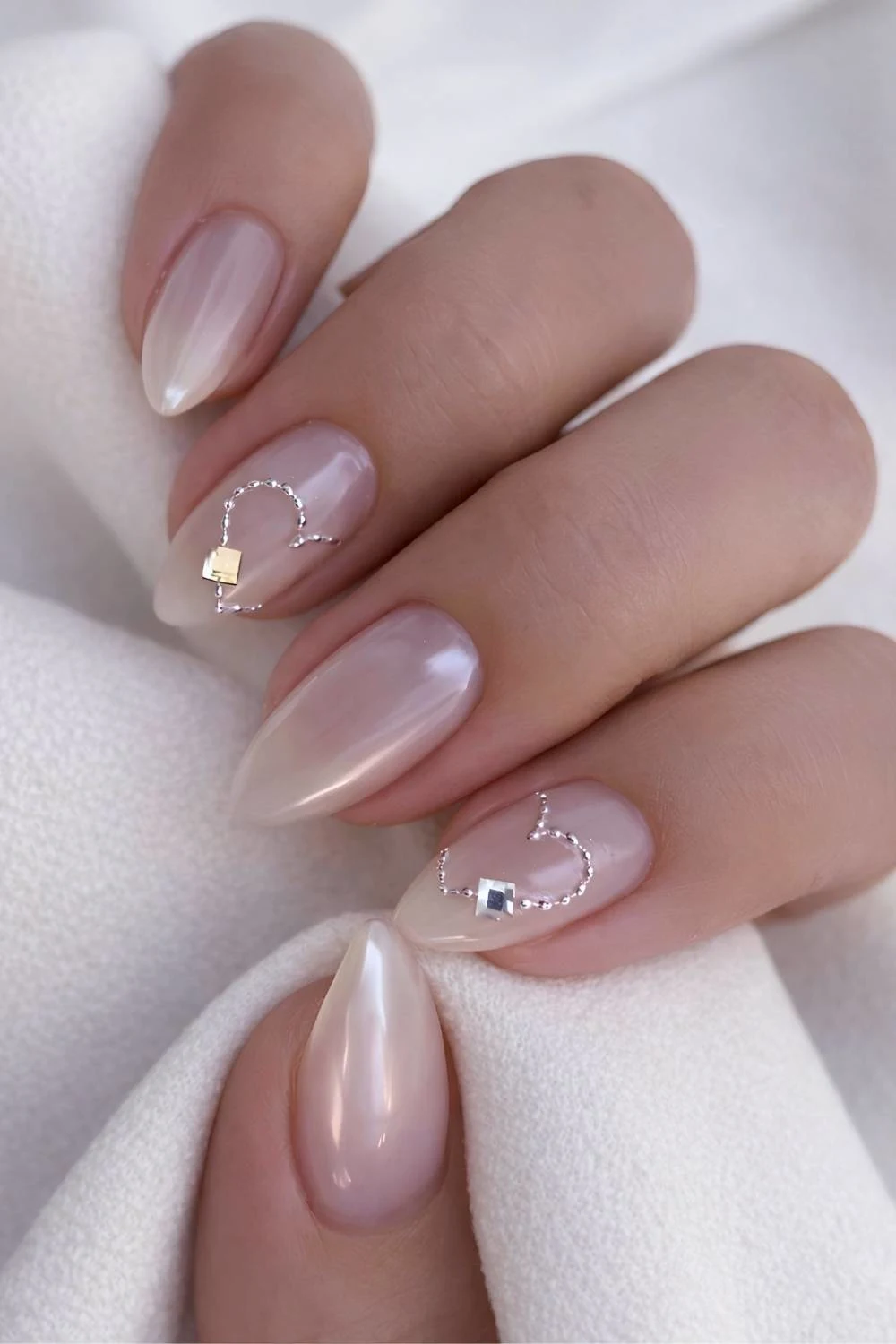 Sheer white chrome nails with hearts and gems