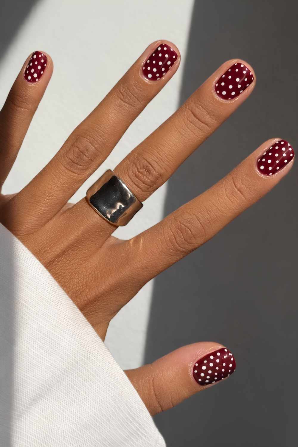 Short burgundy nails with polka dots