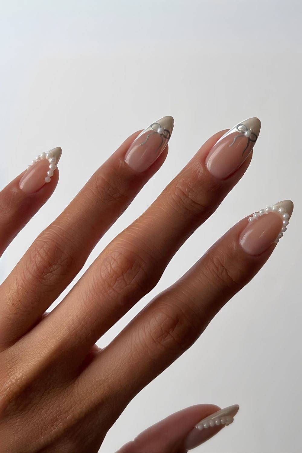 White chrome French tip nails with bows and pearls