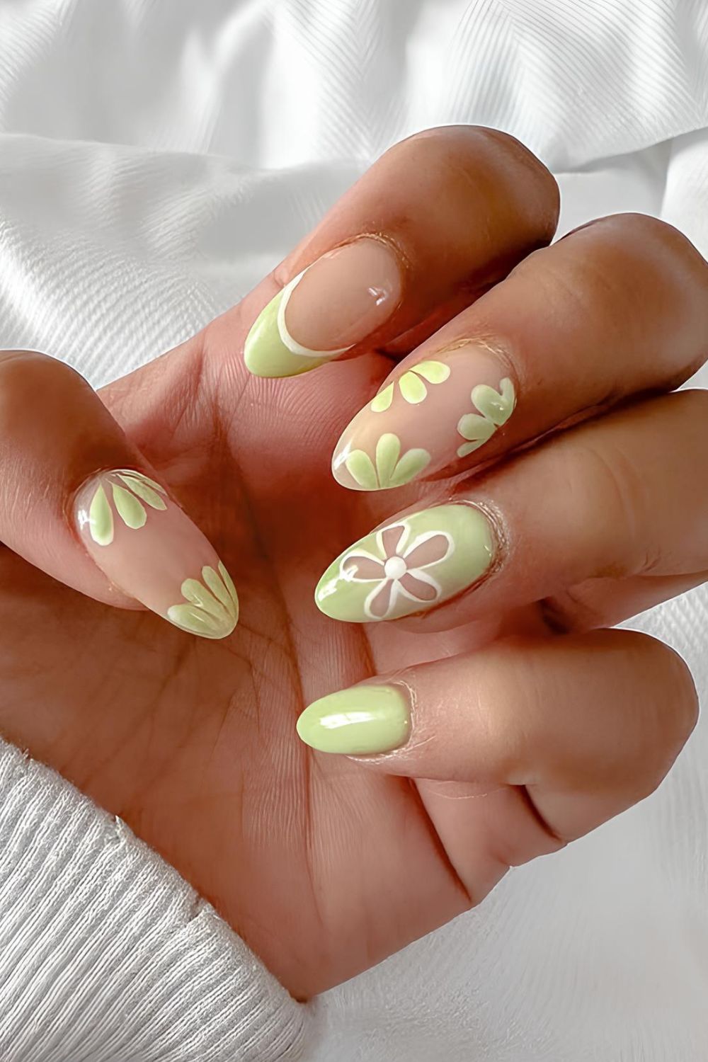 Light green nails with floral accents and a French tip accent