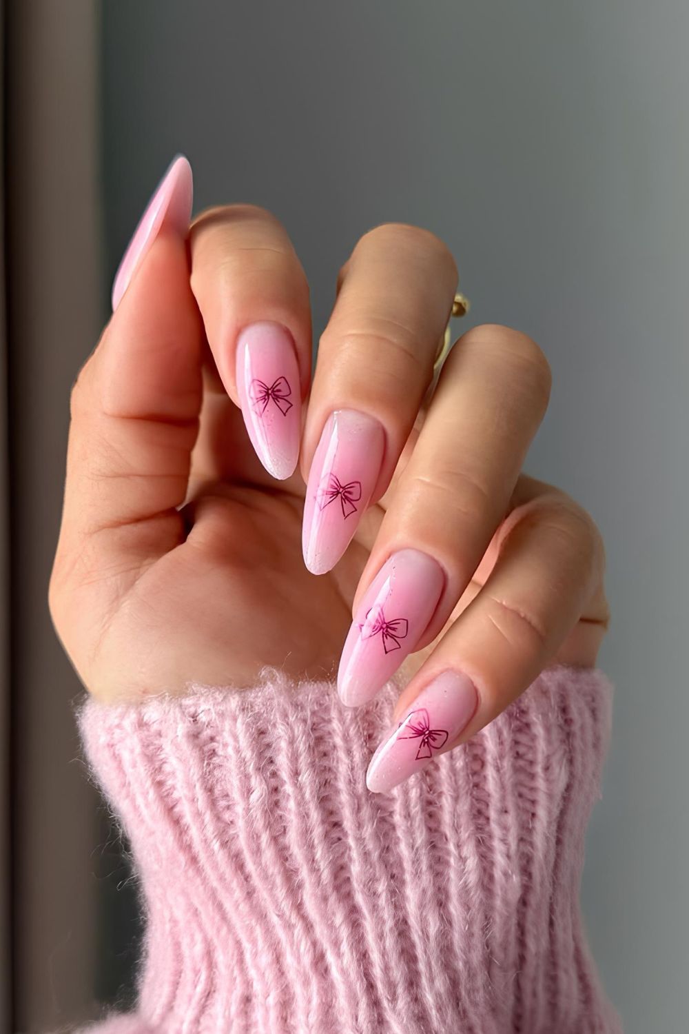 Soft pink nails with bow accents.