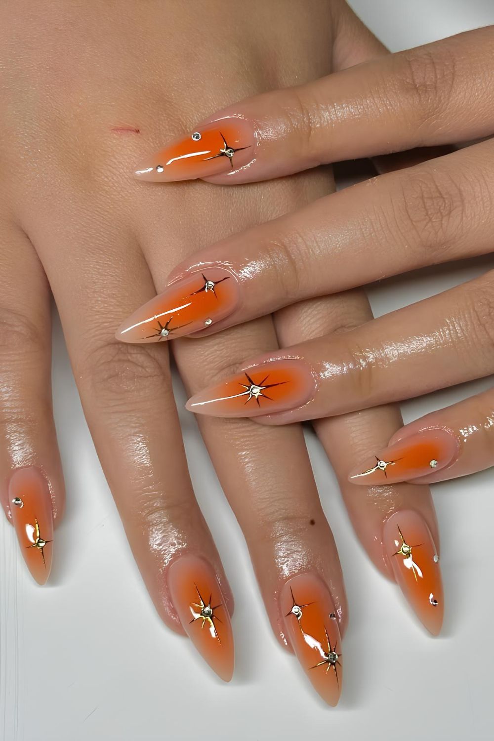 Orange aura nails with stars and rhinestones