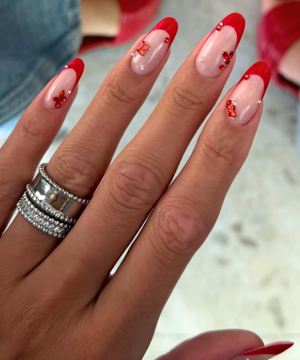 Red French nails with micro butterflies and gems