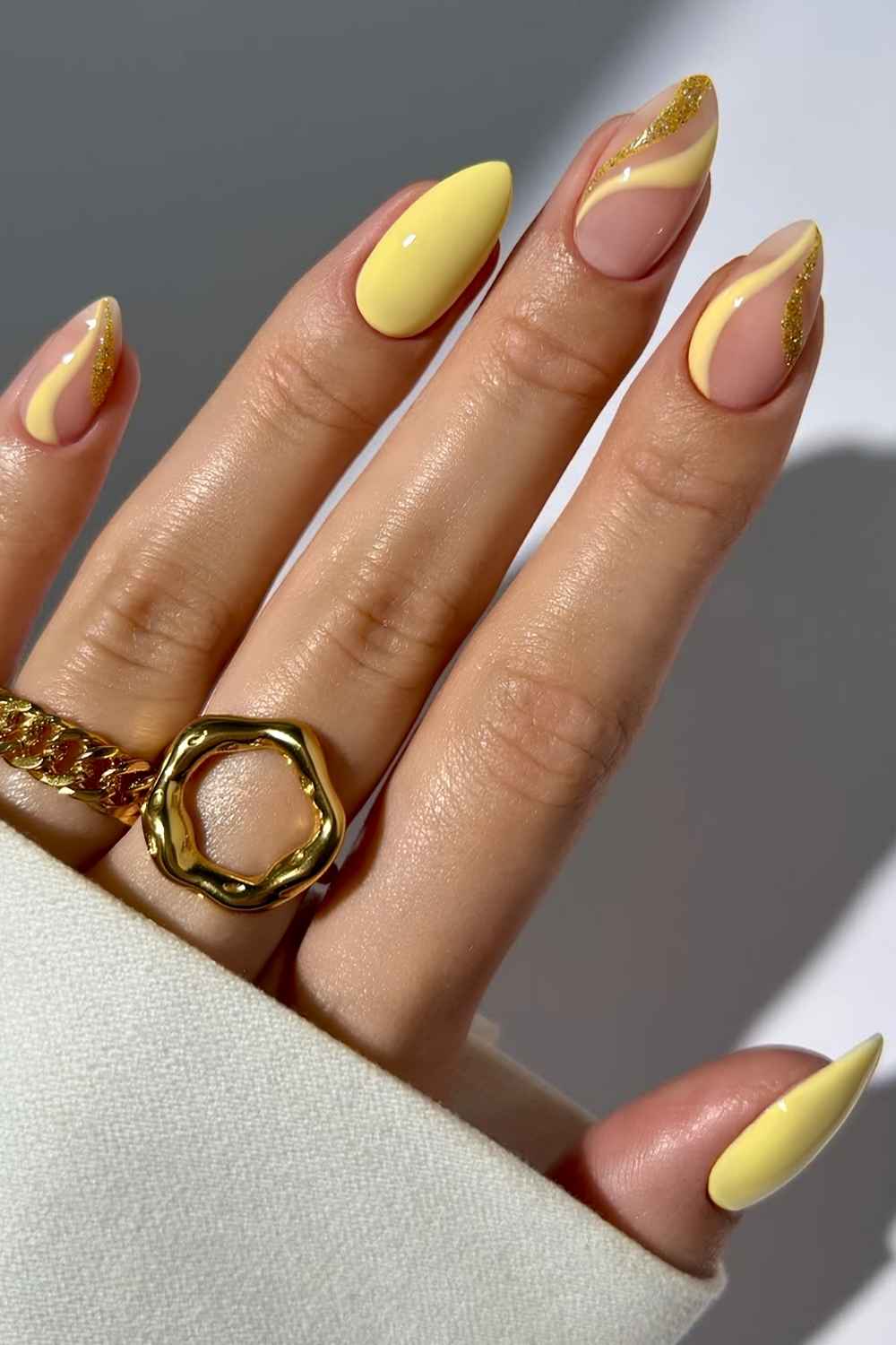 Soft yellow nails with glitter and swirl art