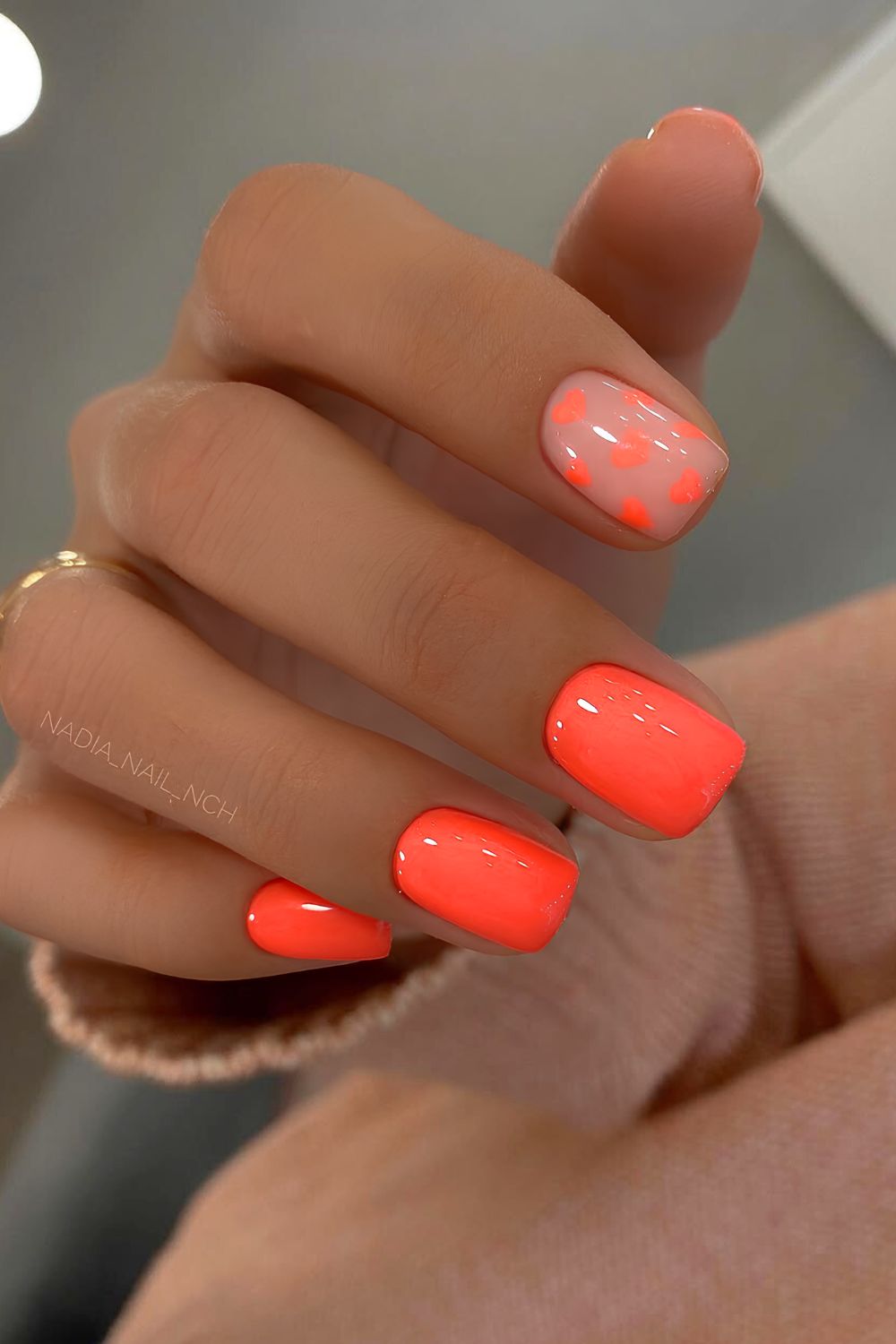 Bright orange nails with heart accents