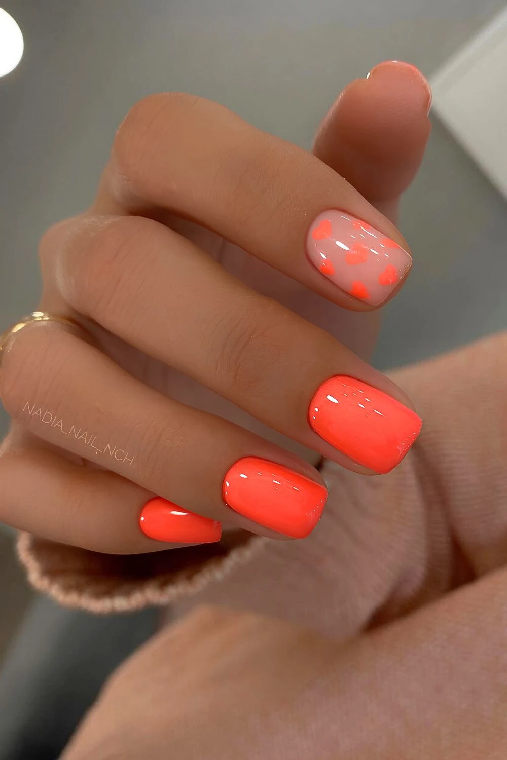 Bright orange nails with heart accents