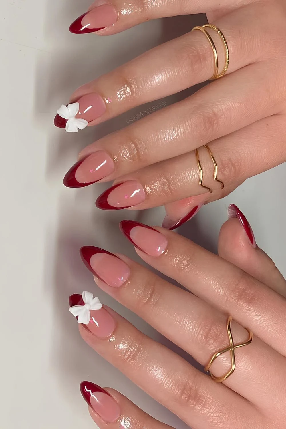 Cherry red French almonfd mani with 3D white bow accent