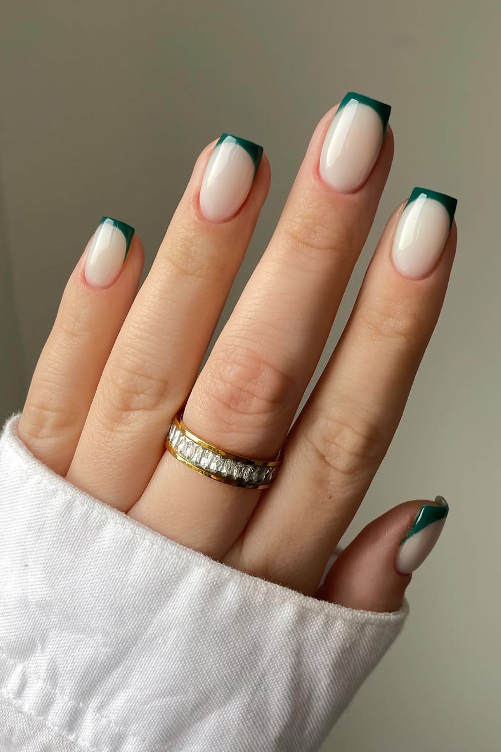 Emerald green French tip nails on a milky base
