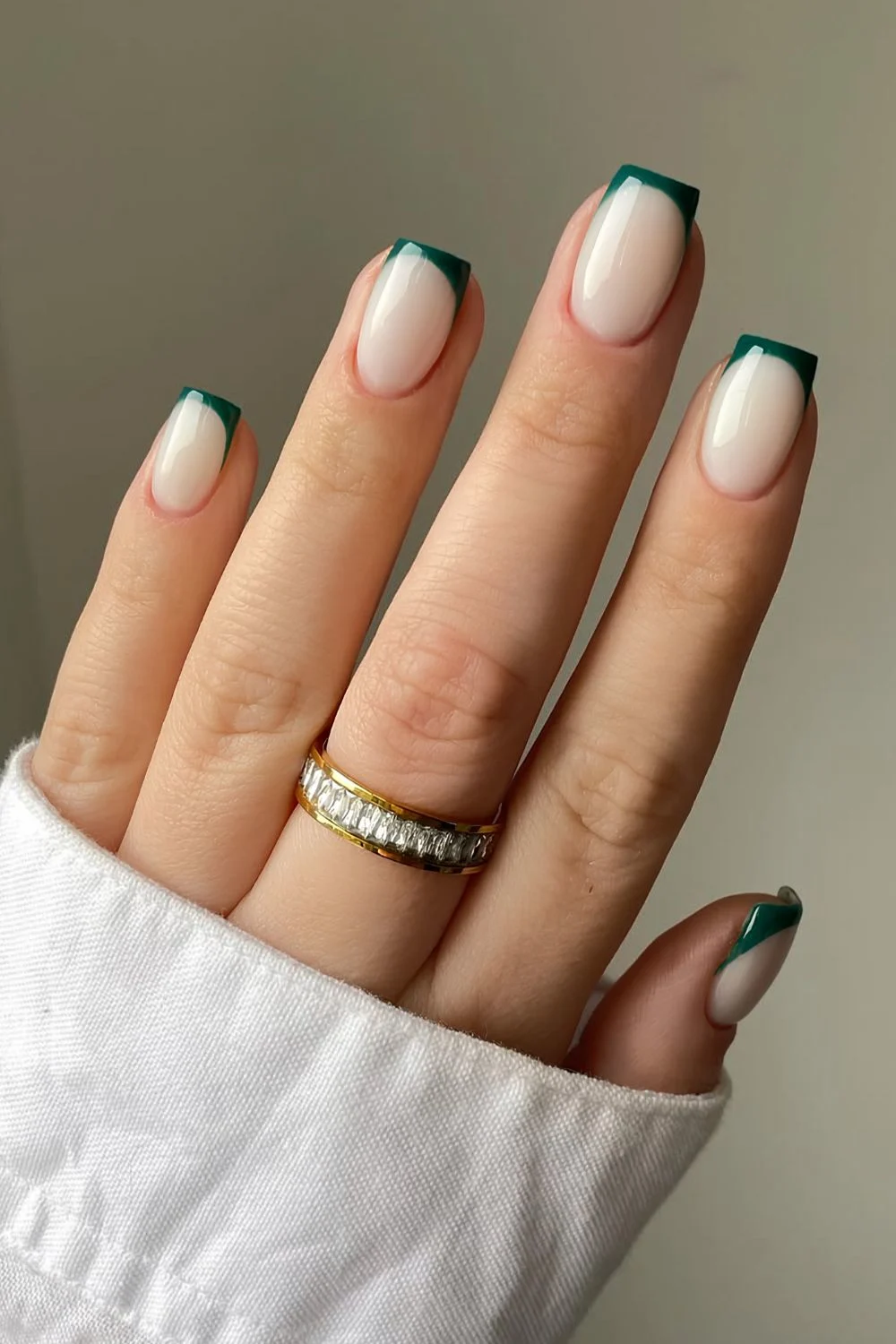 Emerald green French tip nails on a milky base